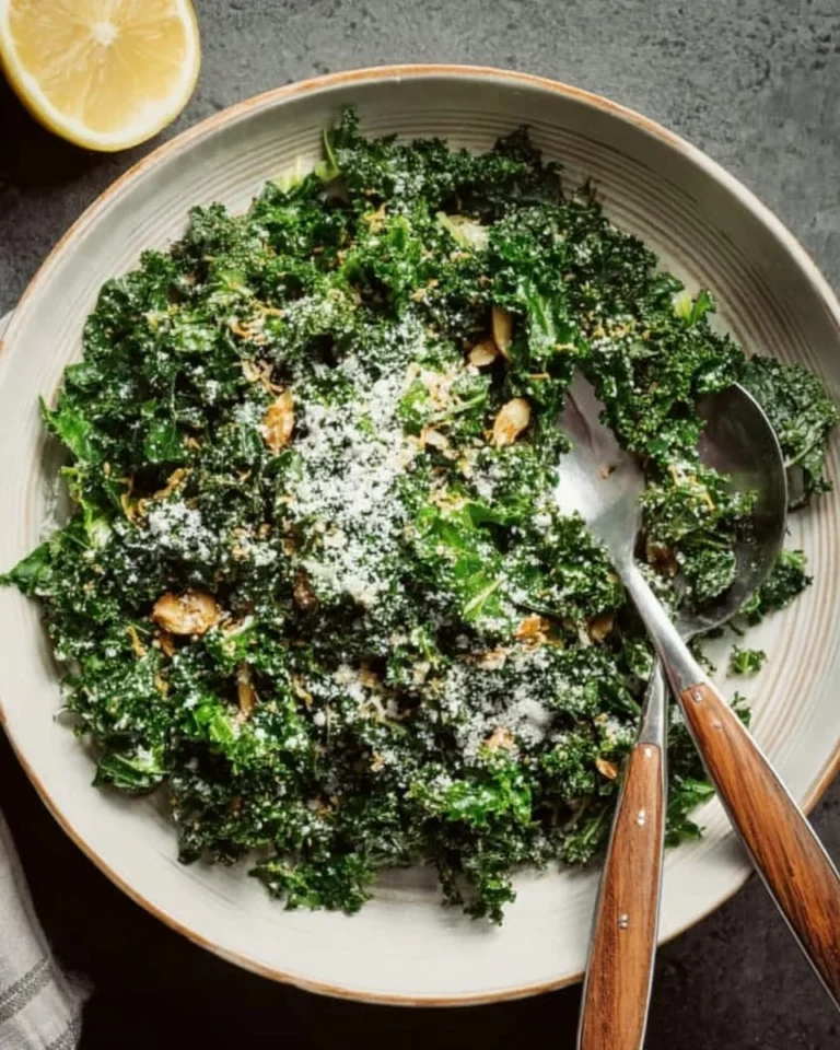 A vibrant bowl of Lemon Parm Kale Salad with lemon slices and parmesan cheese.