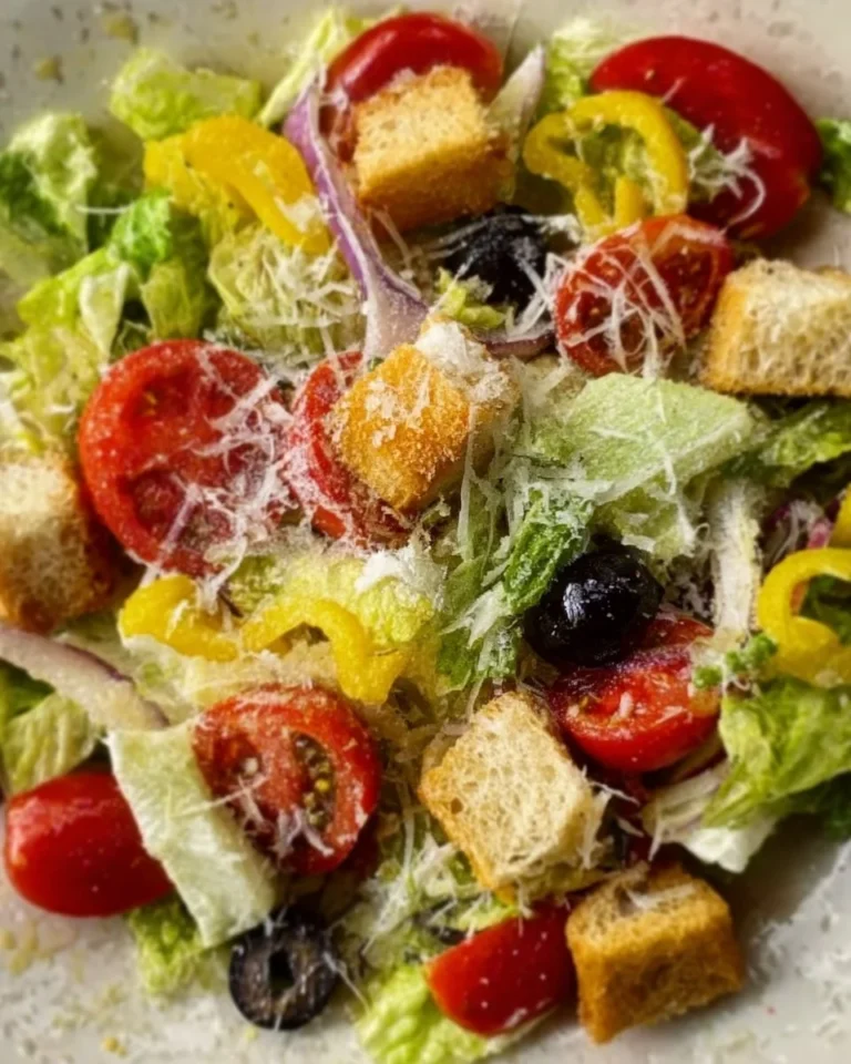 A fresh bowl of Olive Garden Salad with greens, olives, and dressing.