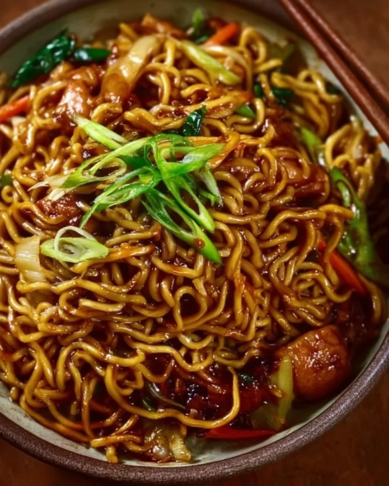 Delicious sticky garlic chicken noodles served in a bowl with fresh vegetables.