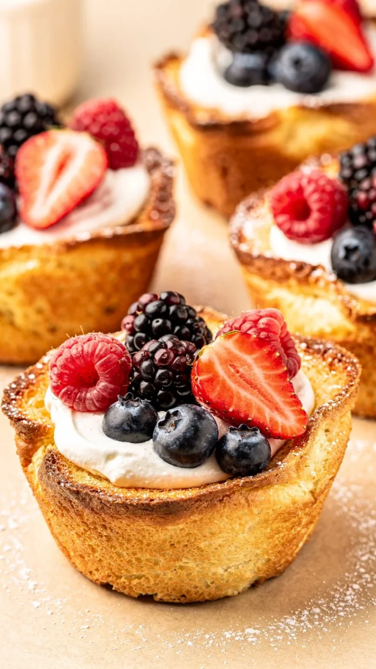 French Toast Cups ready to serve, garnished with berries and syrup.